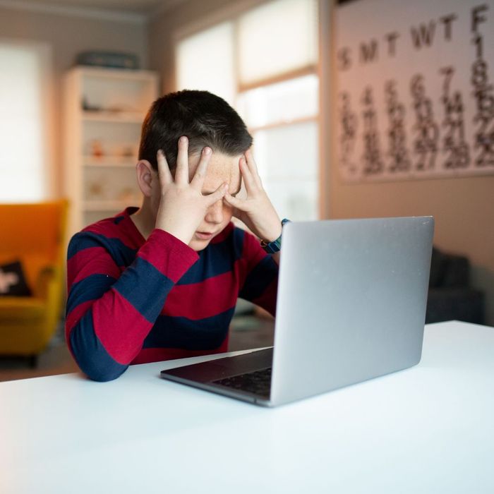 young boy at his laptop rubbing his eye