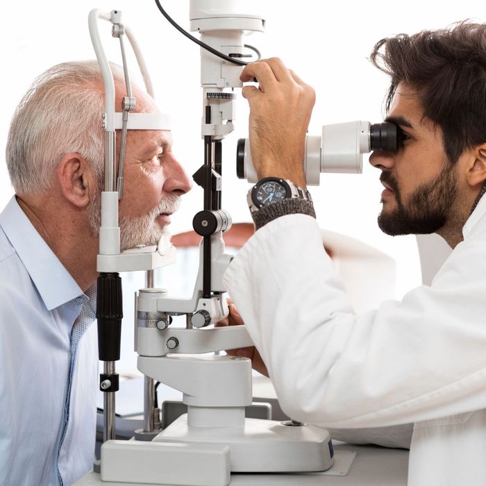 Eye doctor using a diagnostic tool to look into a man's eye. 