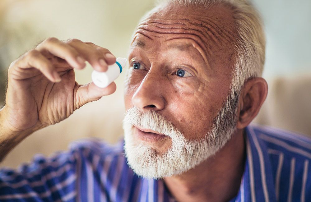 Photo of an elderly man putting in eye drops