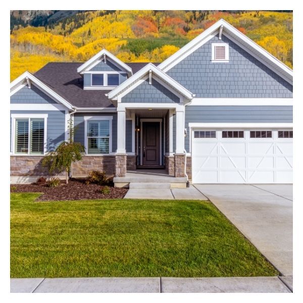 tidy lawn, nice blue house, fall colors in background