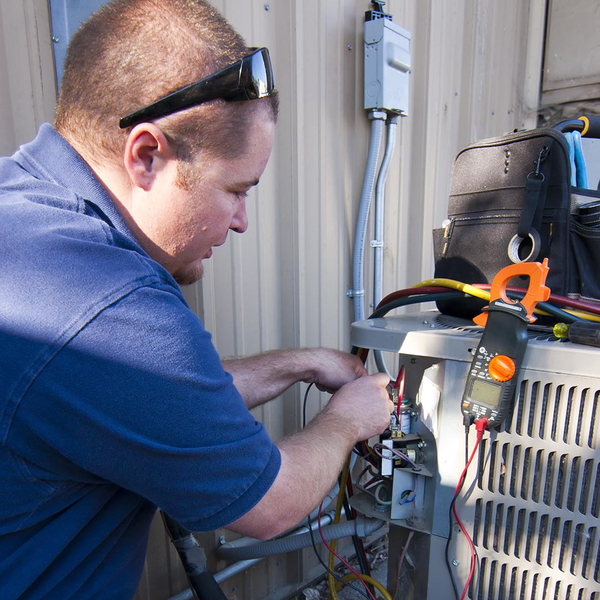 hvac technician performing maintenance on an ac unit