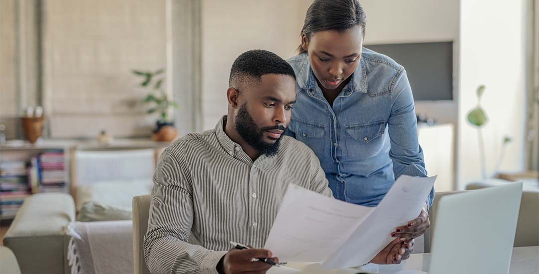 Couple holding papers discussing high bills