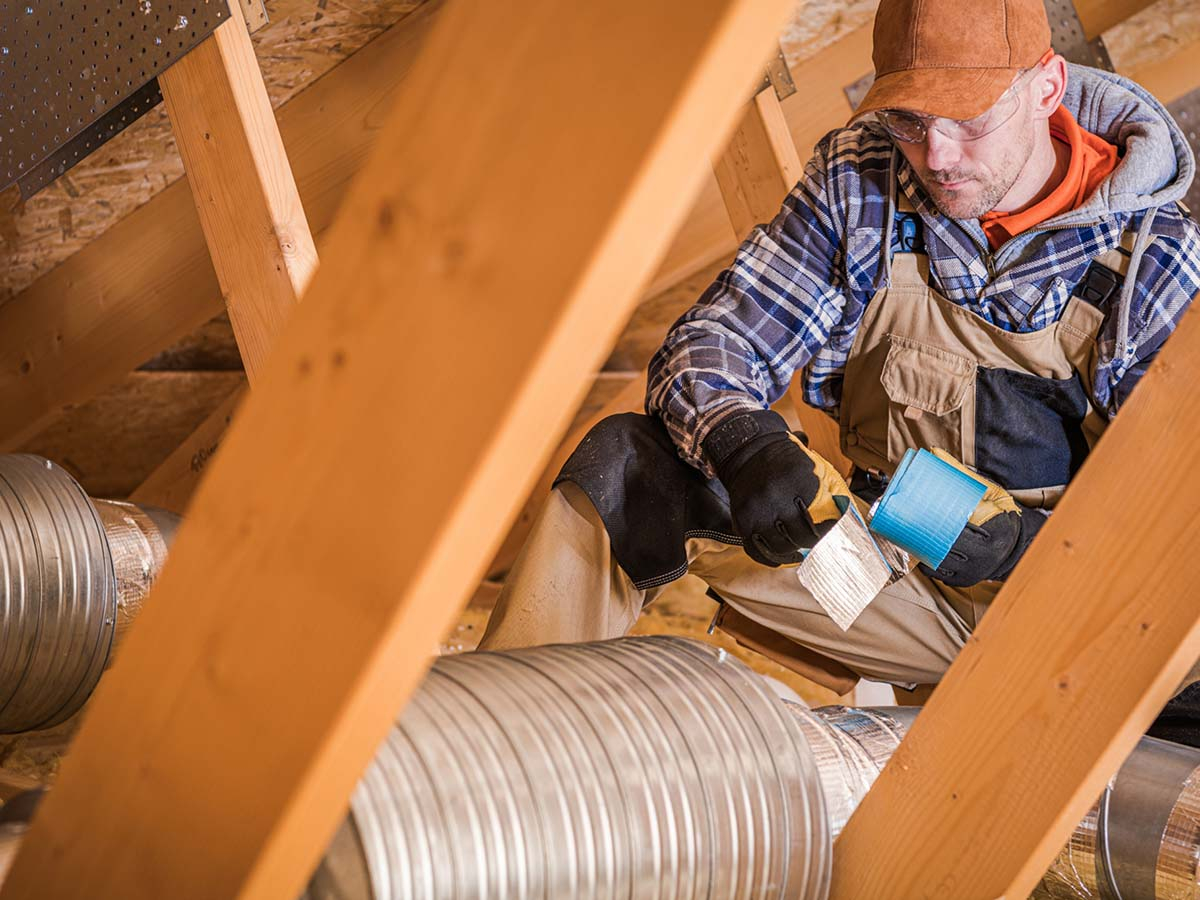 An HVAC repairman fixing an attic unit