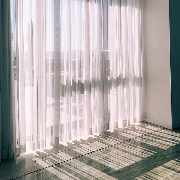 sun shining through floor-length curtains