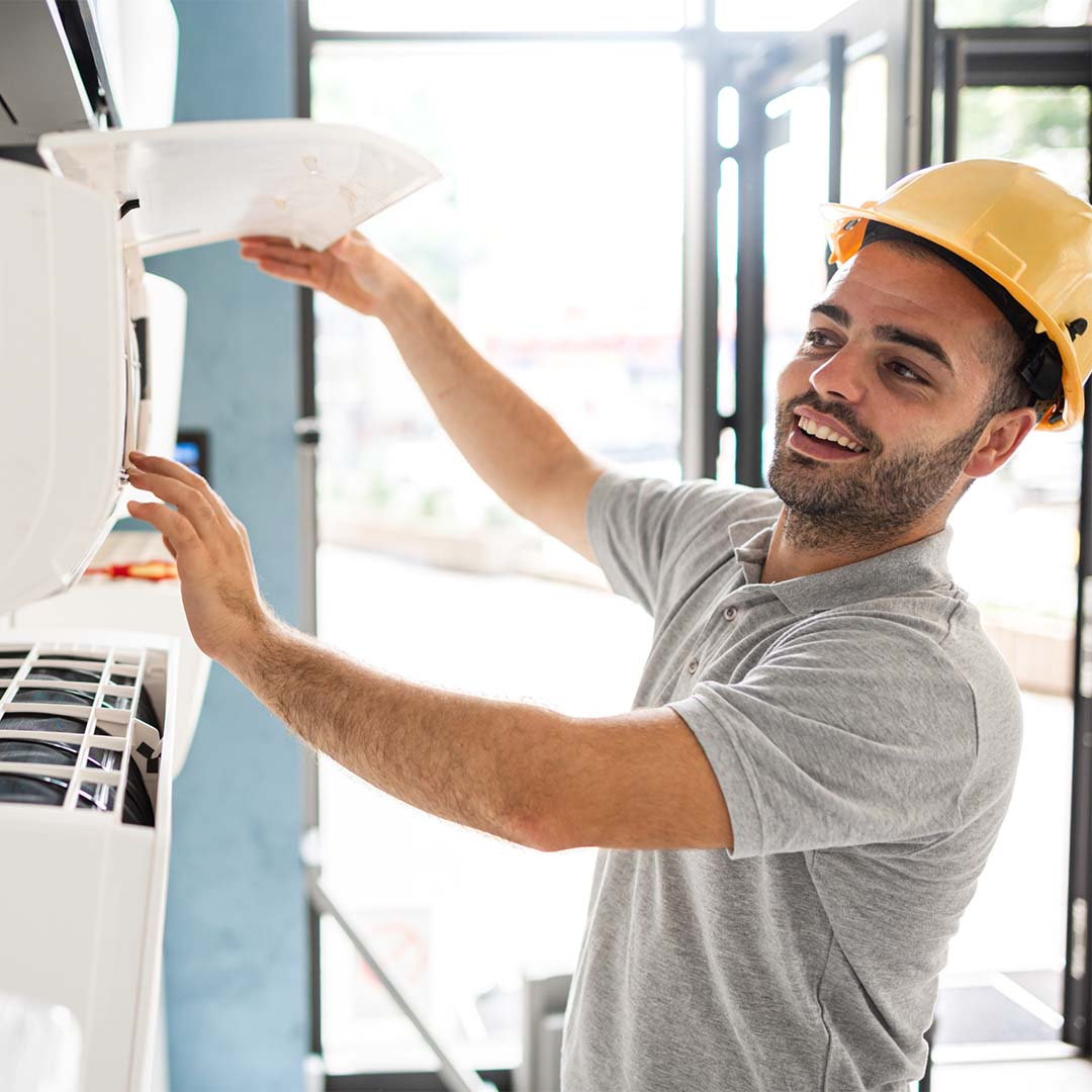 happy technician working on ac unit happy technician working on ac unit