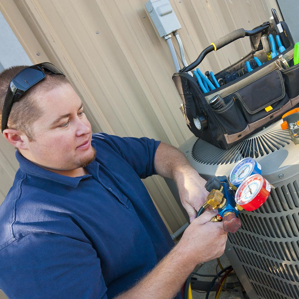 hvac technician performing maintenance on an ac unit 