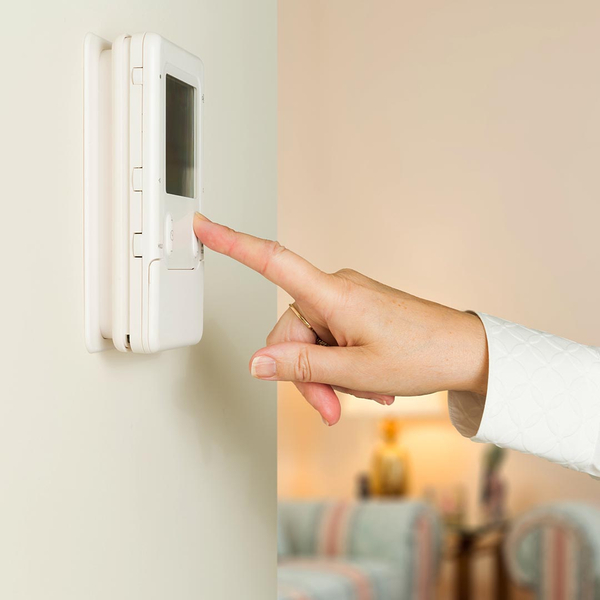 woman pressing a button on a thermostat