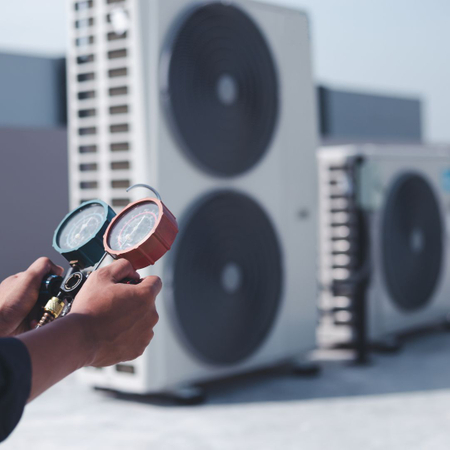 HVAC technician inspecting commercial outdoor HVAC equipment for a multi-family residential project.