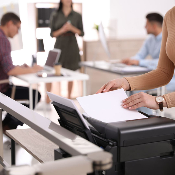 woman using a printer while others are trying to work