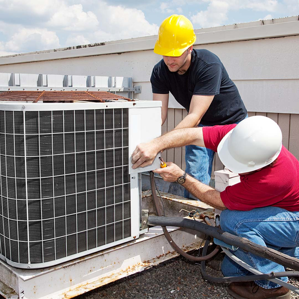 Two HVAC workers repairing AC unit