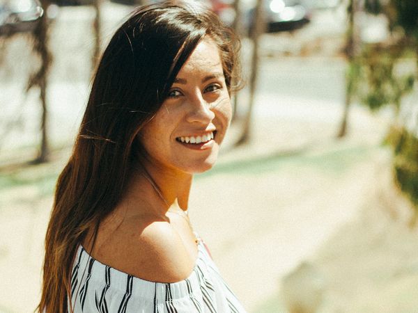 woman out in the sun looking back over shoulder smiling