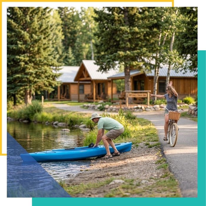 a guest launching a complimentary blue kayak into Mitchell Creek. Another smiling guest on a cruiser bicycle rides along the adjacent paved trail, emphasizing the free outdoor activities available at this Traverse City motel
