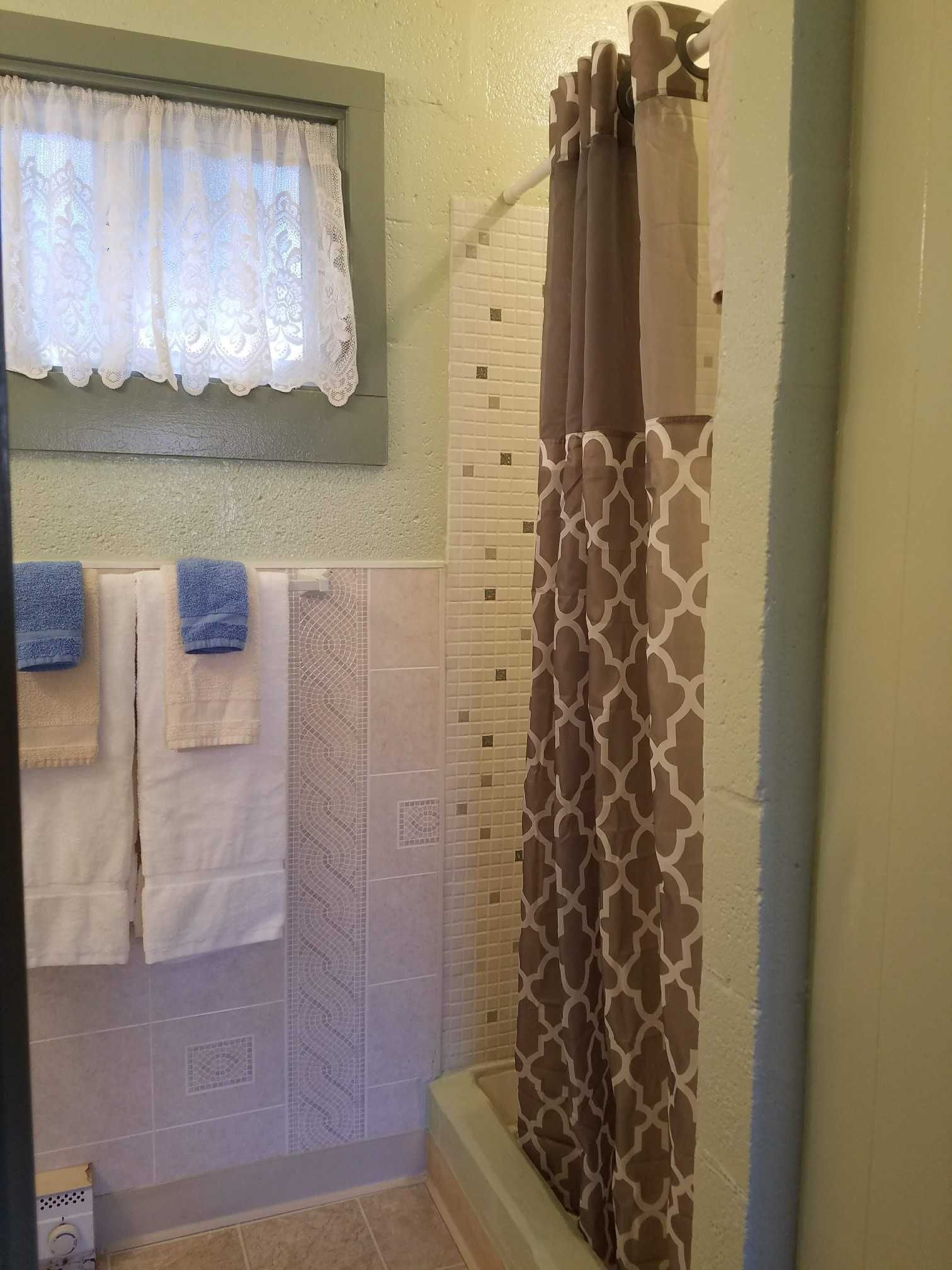a green and tan tiled bathroom  with a shower stall