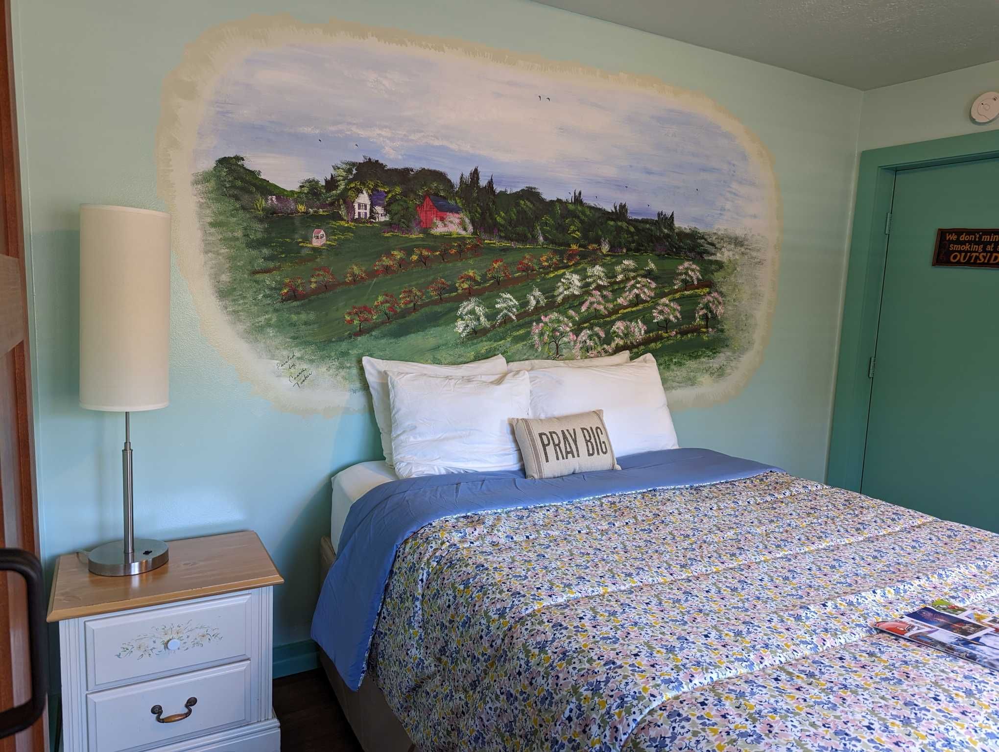 a light green room with an cherry orchard mural