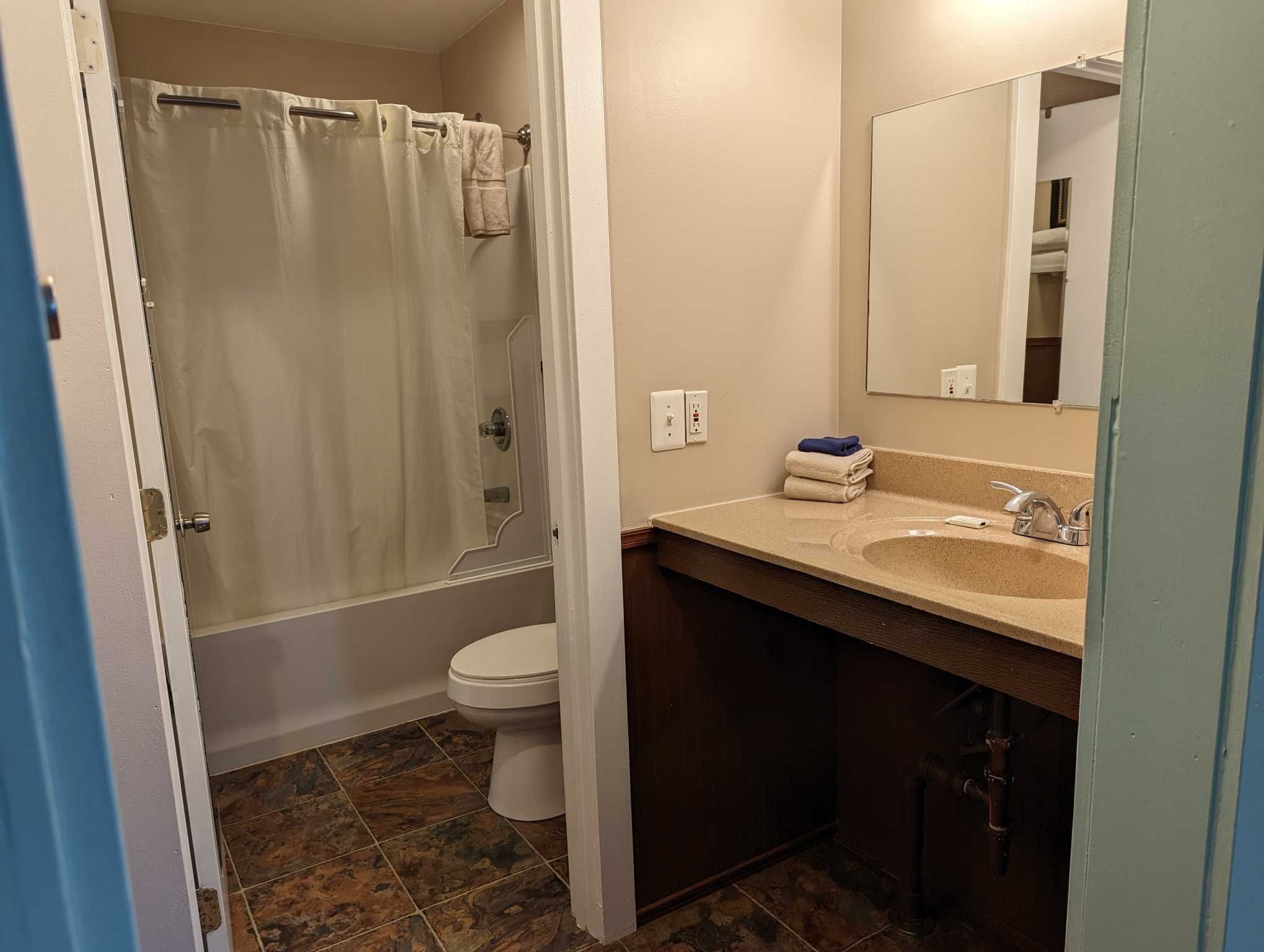 a large bathroom with a single sink vanity, and a shower and tub