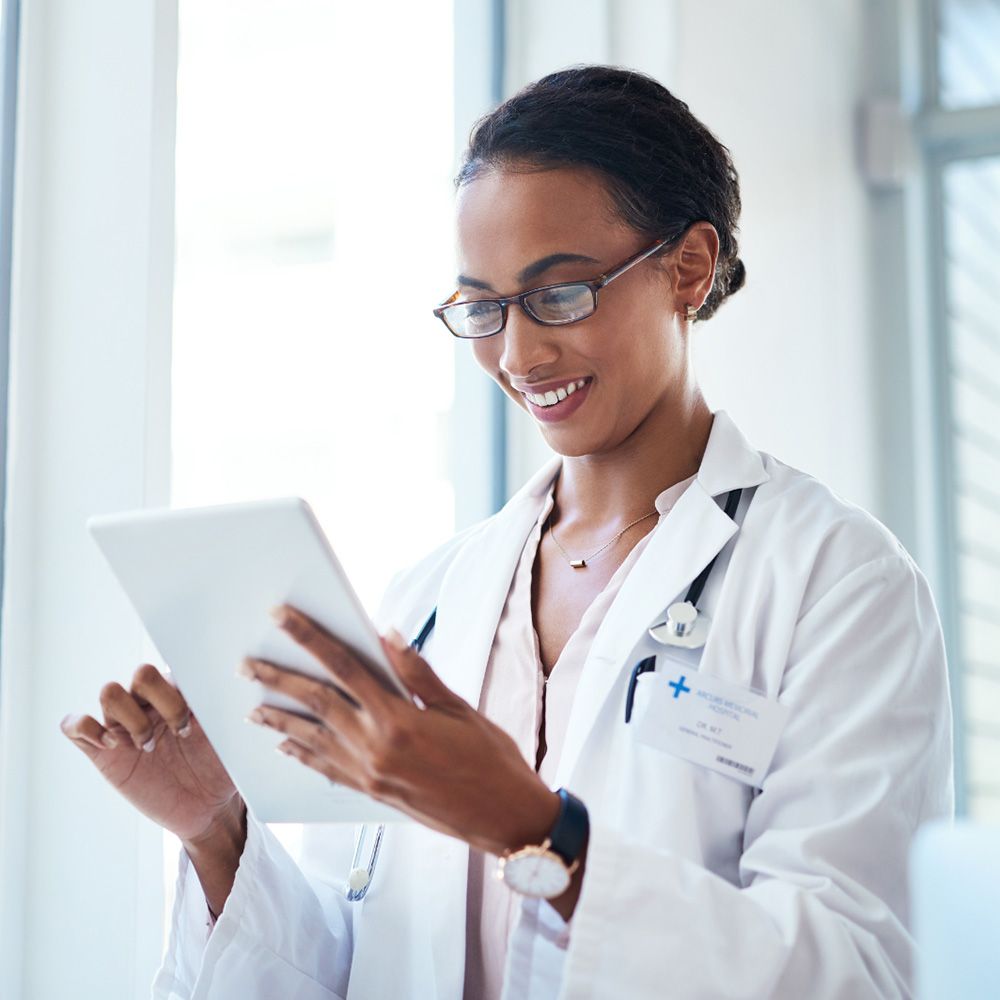 A doctor smiling while looking at her tablet A doctor smiling while looking at her tablet