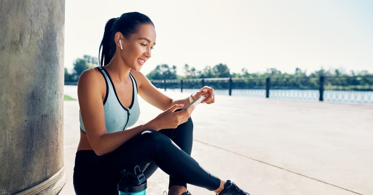 A young woman looking at her phone after exercising outside