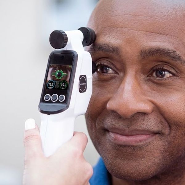 technician performing an eye pressure measurement on a smiling patient