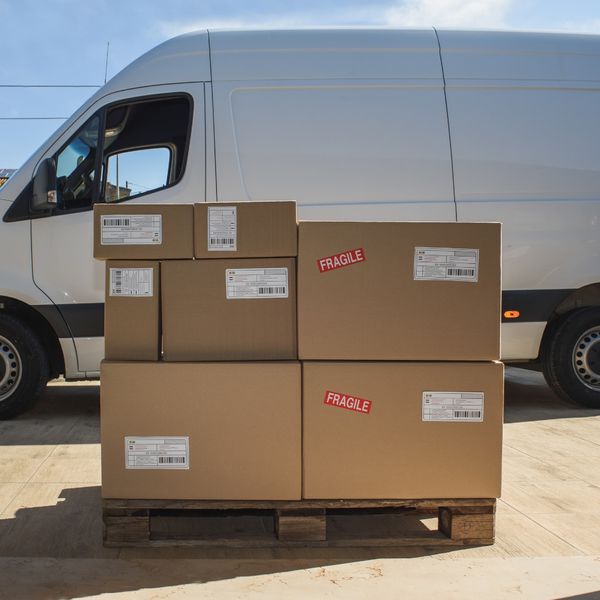 Stack of shipping boxes on a pallet next to a van