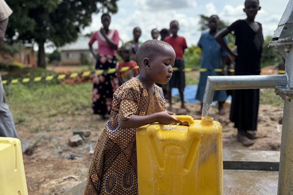 Girl filling up gallon bucket of water Girl filling up gallon bucket of water