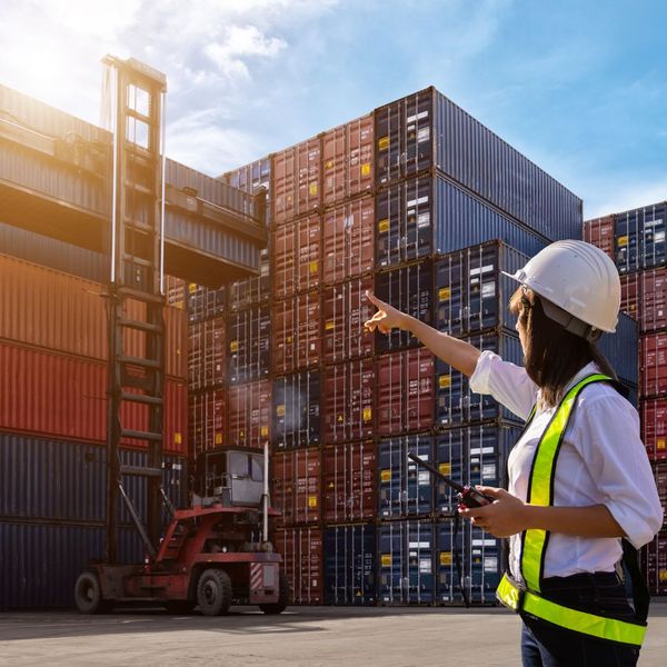 woman in yellow vest organize cargo containers