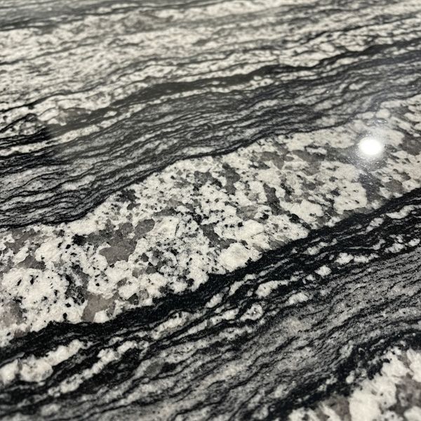 Close-up of a polished granite countertop slab showing intricate natural stone patterns and a high-gloss finish.