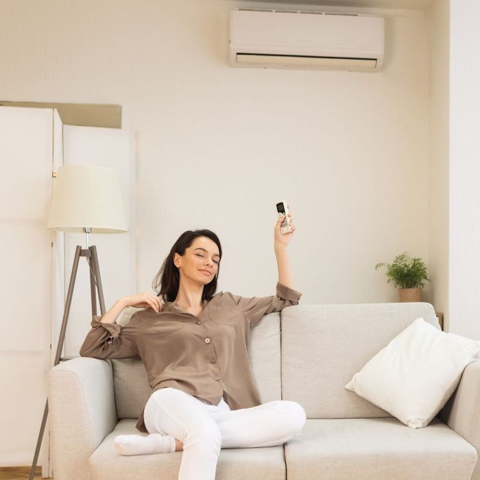 woman turning on AC system