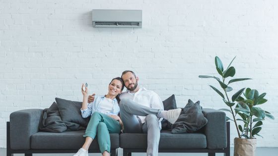 Couple sitting on a couch near an AC unit