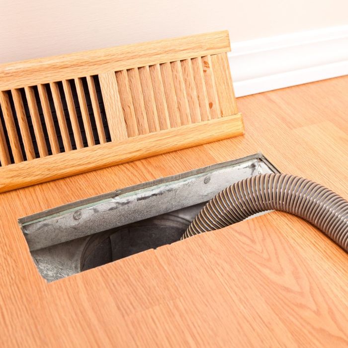 A duct cleaning tube inserted into a floor air duct