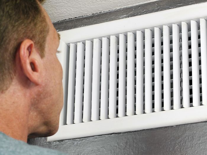 man looking into heater vent