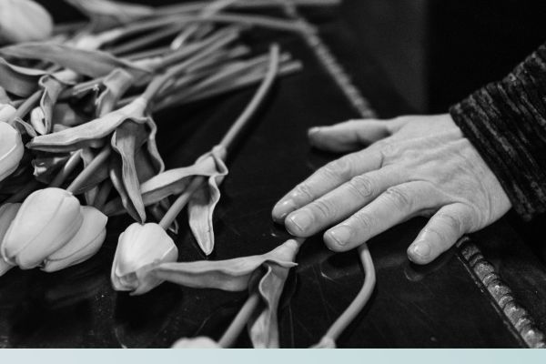 Hands touching a coffin with flowers Encinitas2.jpg