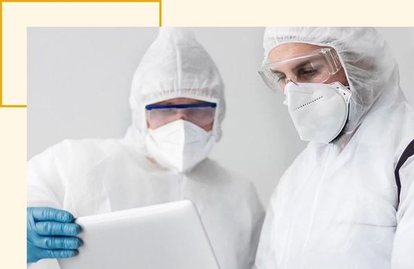2 workers in biohazard suits reviewing a tablet