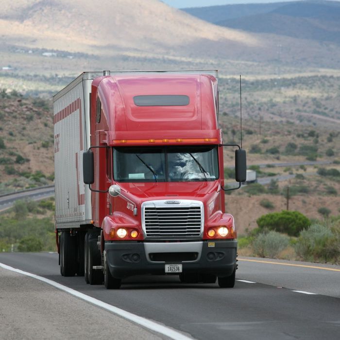 Red truck driving on curving road through mountains