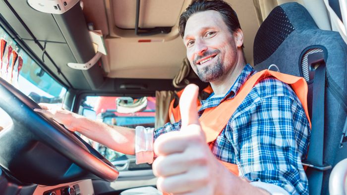 Truck driver in driver's seat giving a thumbs up