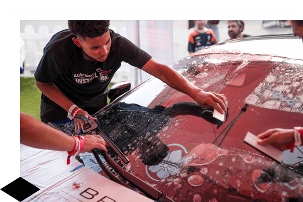tech smoothing out the new windshield skin on a car