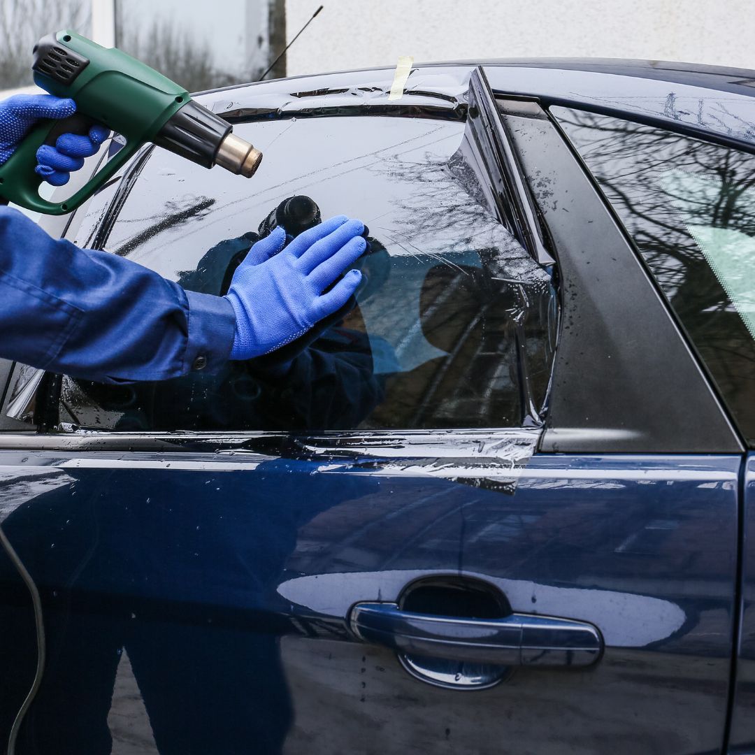 a person applying a window tint to a blue car