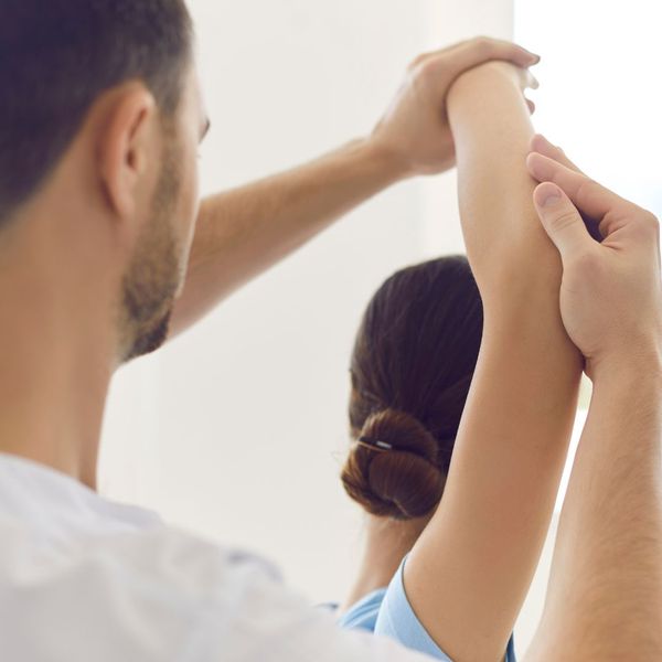 woman stretching arm overhead with physical therapist woman stretching arm overhead with physical therapist