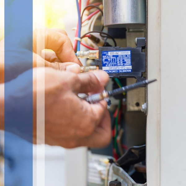 Technician repairing electrical wiring on an air conditioner component.