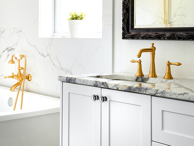 Close up of a sink with granite a countertop and gold trim