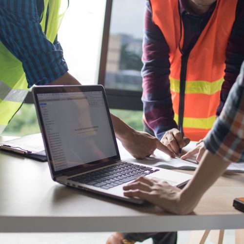 Construction workers around a laptop