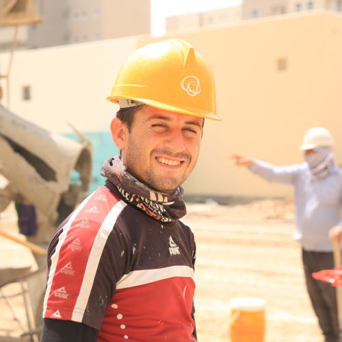 Smiling construction worker wearing a yellow hard hat outdoors