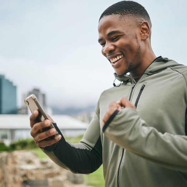 person in fitness attire smiling looking at phone