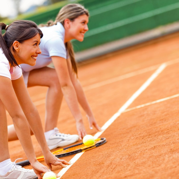 smiling girls on tennis court racing