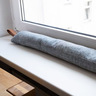 A pillow placed in front of a drafty window