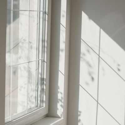 A double-hung window casting shadows on a white wall