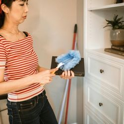 Image of a woman dusting things on a shelf