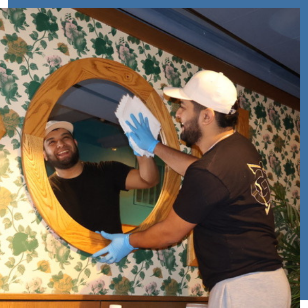 man wiping down mirror in commercial building