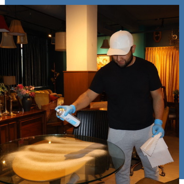 man sanitizing glass table in restaurant