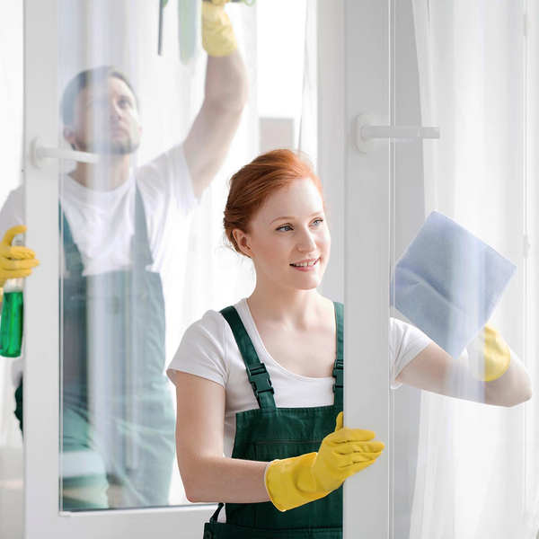 Happy woman and man cleaning windows on doors