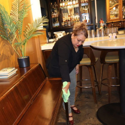 woman wiping down restaurant seat